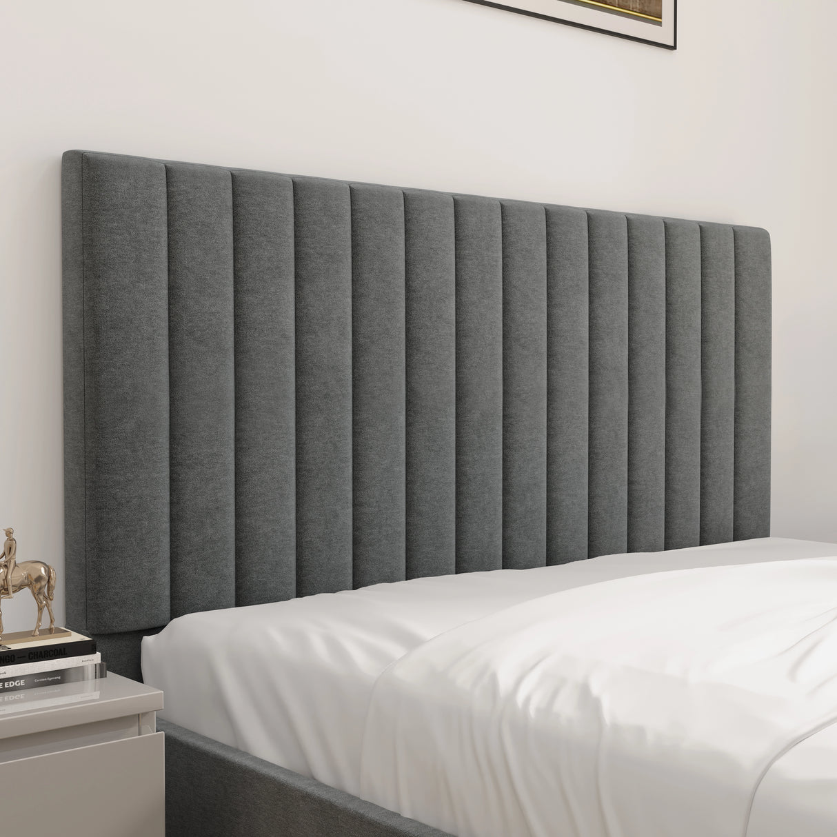 Gray upholstered headboard on a bed with white bedding in a bedroom setting.