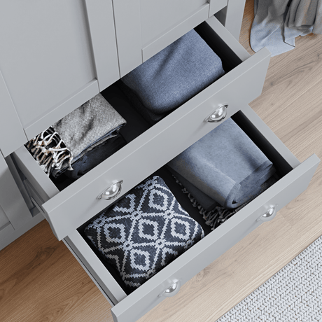 Top view of open grey wardrobe drawers with neatly folded clothes inside, from shaker style bedroom furniture sets UK.