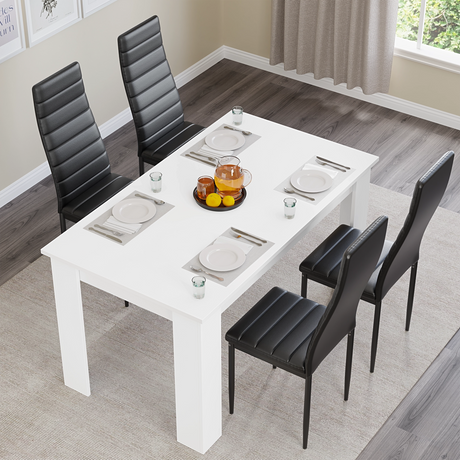 Top view of modern white dining table set with black chairs, set for four. Ideal for stylish kitchen or dining room interiors.