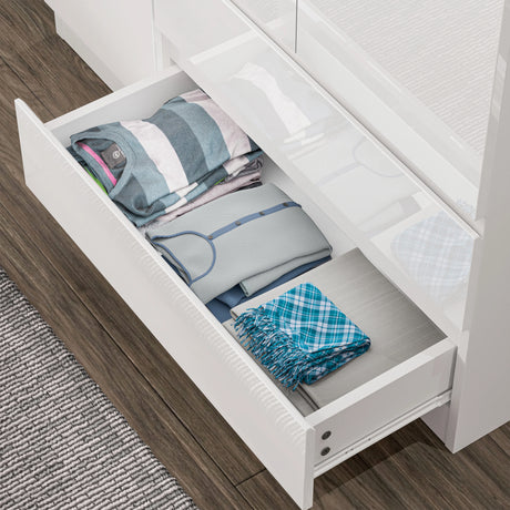 Open drawer of white high gloss wardrobe displaying neatly folded clothes, showcasing ample storage space and smooth glide mechanism.