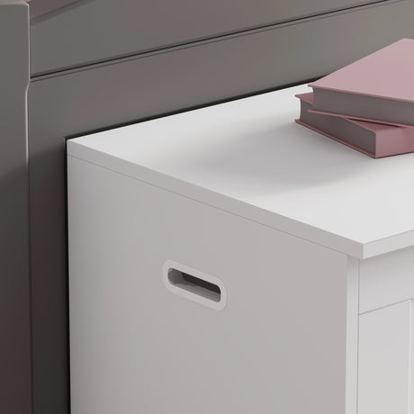 White storage unit with a handle next to a gray cabinet with pink books on top.
