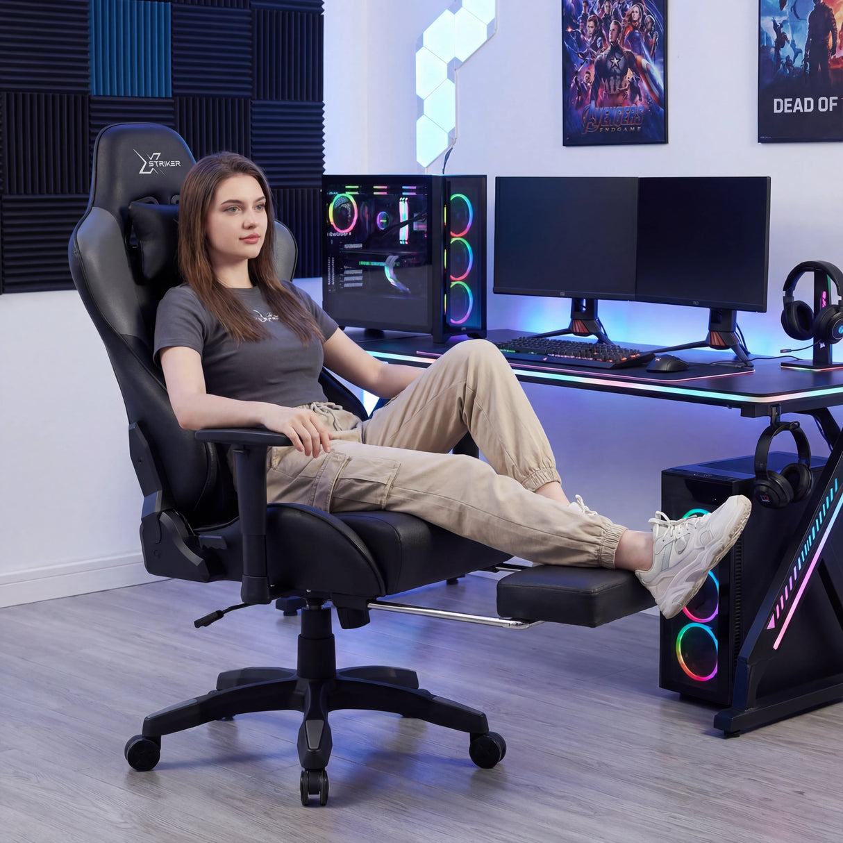 Comfy Gaming Chair with Footrest, Wide Seat & 3D Armrest Xstriker in black, shown in a modern gaming setup with a woman reclining comfortably. Ideal for long PC or office sessions.