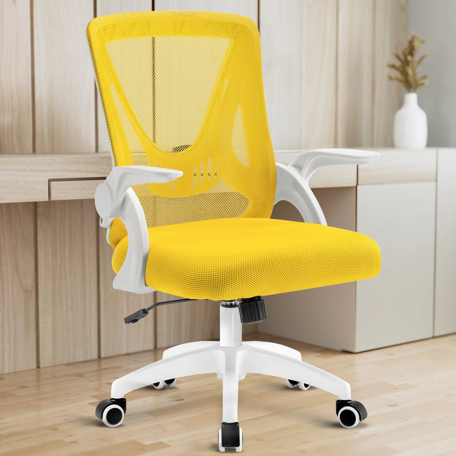 A yellow mesh chair in a home office provides ergonomic support, with a working desk in the backdrop.