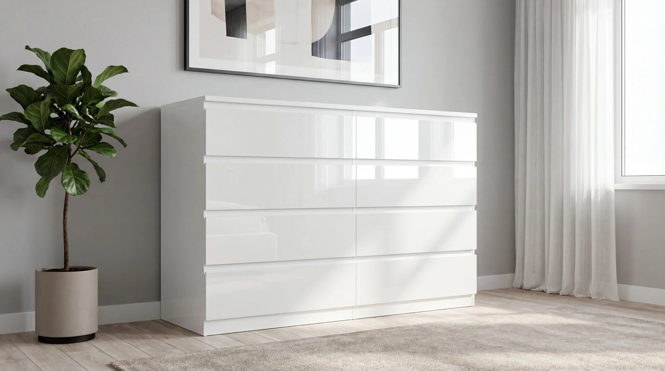 Gloss white chest of drawers placed in a room, beside a large window with curtains, a planter and a soft rug on the wooden flooring