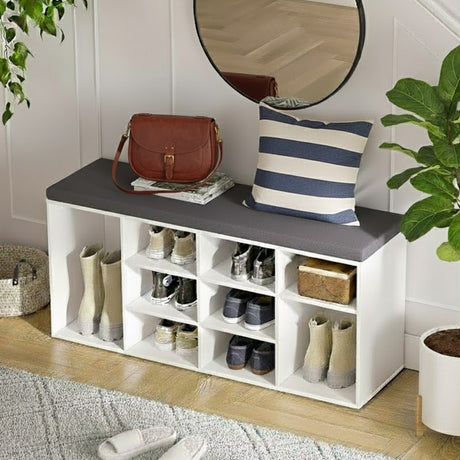 White shoe storage bench with shelves, a round mirror, and decorative items in a room.