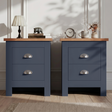 [Blue] Pair of blue bedside table pair on rug, oak-effect tops, chrome cup handles, lamp and books left, vase and frame right