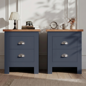 [Blue] Pair of blue bedside table pair on rug, oak-effect tops, chrome cup handles, lamp and books left, vase and frame right