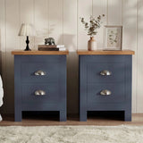 [Blue] Pair of blue bedside table pair on rug, oak-effect tops, chrome cup handles, lamp and books left, vase and frame right