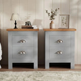 [Grey] Pair of grey bedside table pair on rug, oak-effect tops, chrome cup handles, lamp and books left, vase and frame right