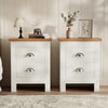 [White] Pair of white bedside table pair on rug, oak tops, cup handles, lamp and books left, vase and frame right