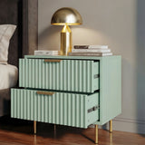 Green nightstand with gold legs and handles beside a bed, displaying two drawers partially open in soft natural lighting