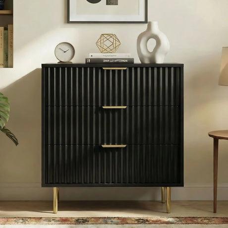 Three drawer black chest of drawers with flutrina detailing and gold legs in a natural light room setting
