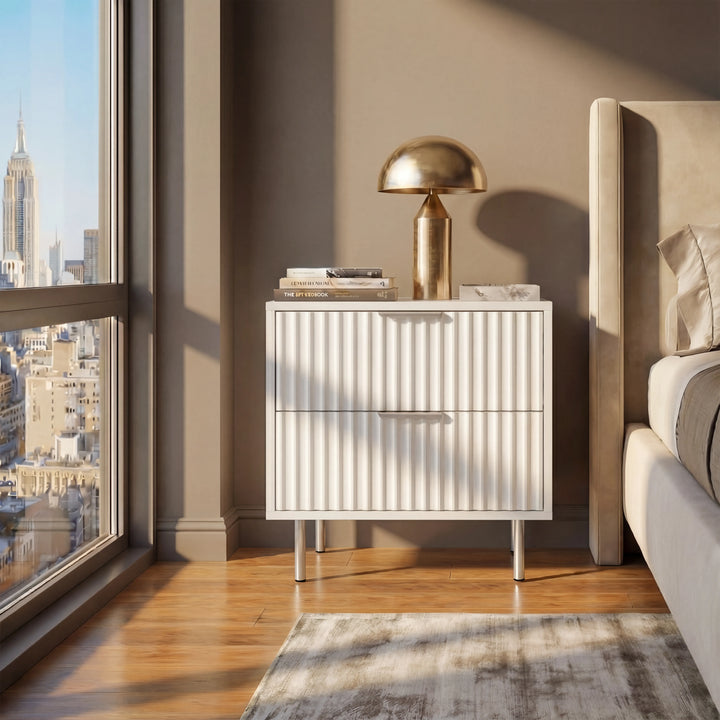 [White] three drawer dresser with flutrina front and silver legs, placed near a window in a bedroom for personal item storage