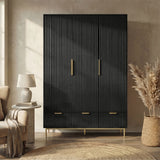 Black flutrina design triple wardrobe with three drawers and golden legs placed against a wall in a natural light room