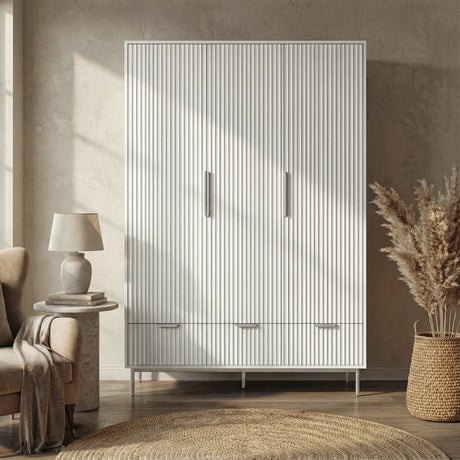 White flutrina design triple wardrobe with three drawers and silver legs placed against a wall in a natural light room