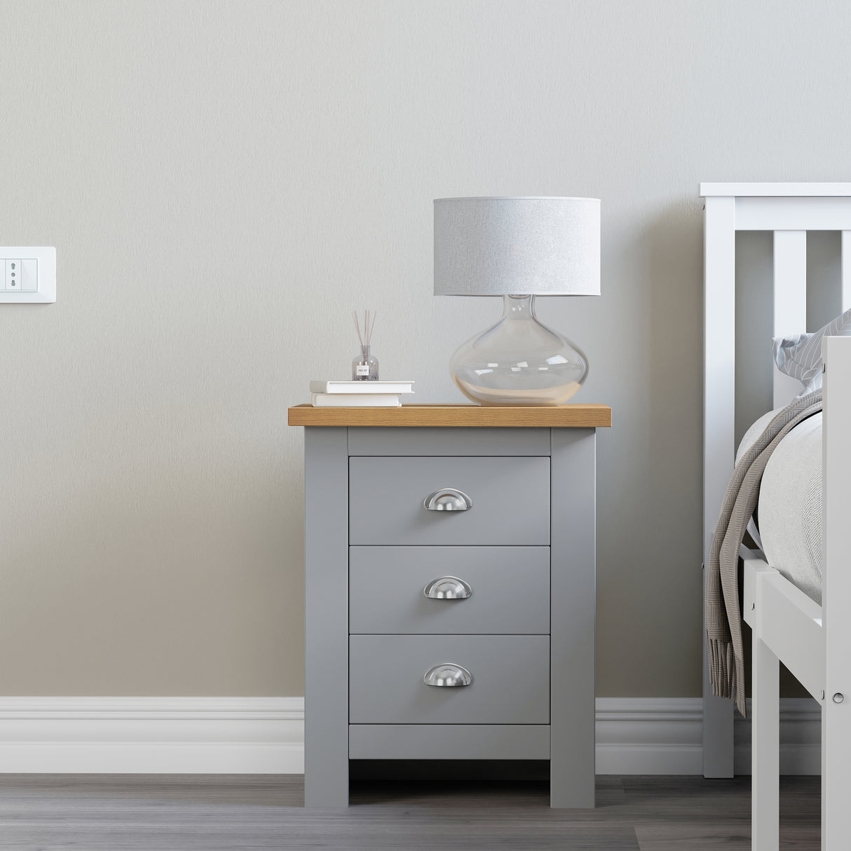  3 drawer bedside table Grey with books and a lamp on top for a cozy, functional touch.