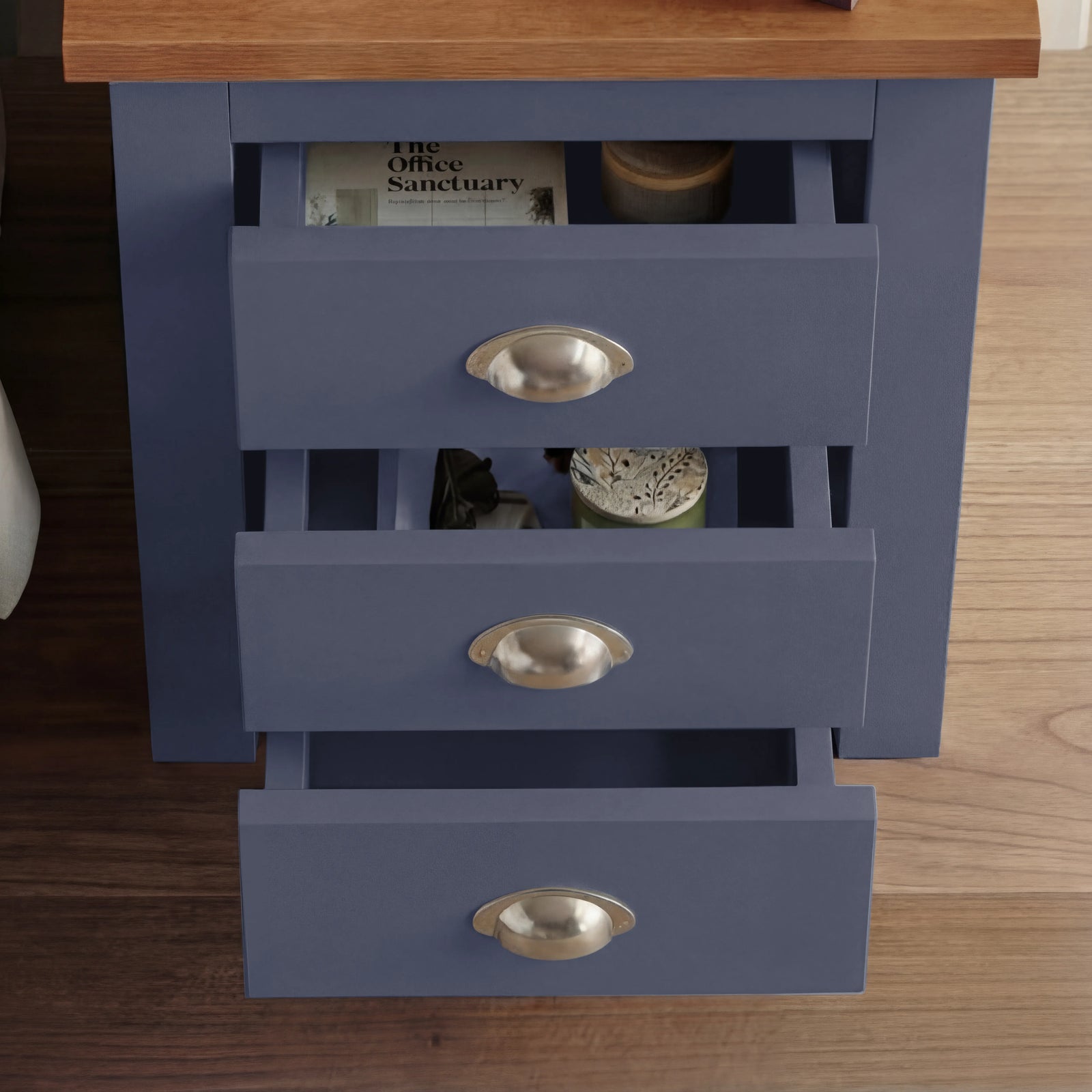 [Blue] Overhead view of blue shaker bedside with all 3 drawers cascade-open, magazine in top drawer