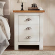 [White] Front view of 3 drawer shaker bedside table with oak top and cup handles styled beside bed with lamp