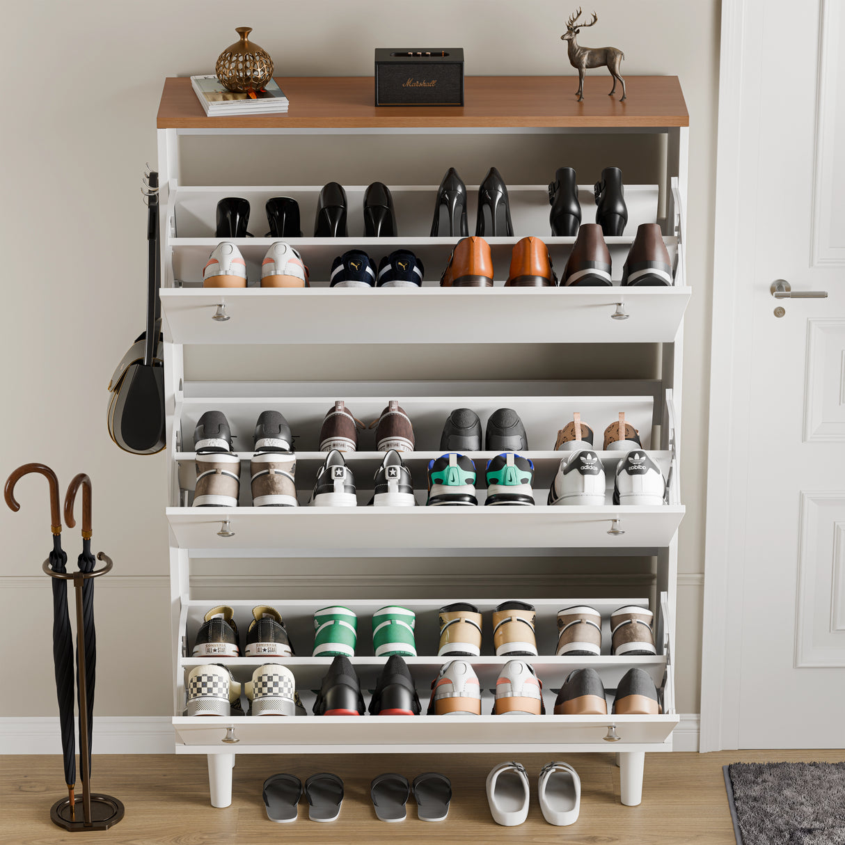 Three door shoe storage cabinet in white oak top open showing 24 shoes, mix of boots, shoes and wellies, music system on top.
