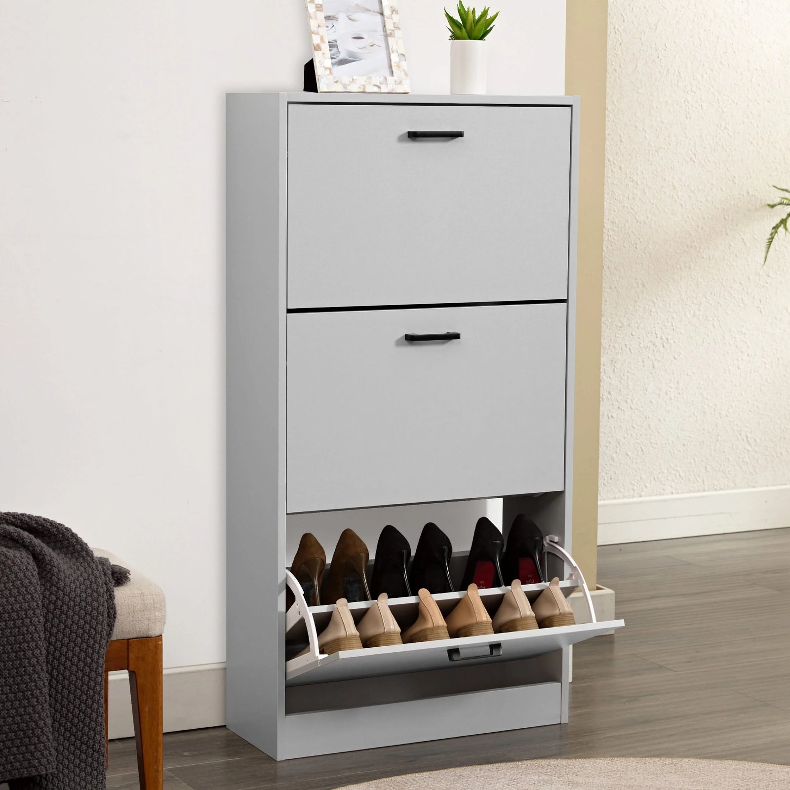 [Light Grey] Tall light grey shoe cabinet, framed art on top, bottom drawer tipped open showing footwear