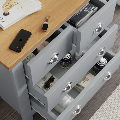 4 drawer 0f chest with open storage, books, and a flower arrangement on the top surface.