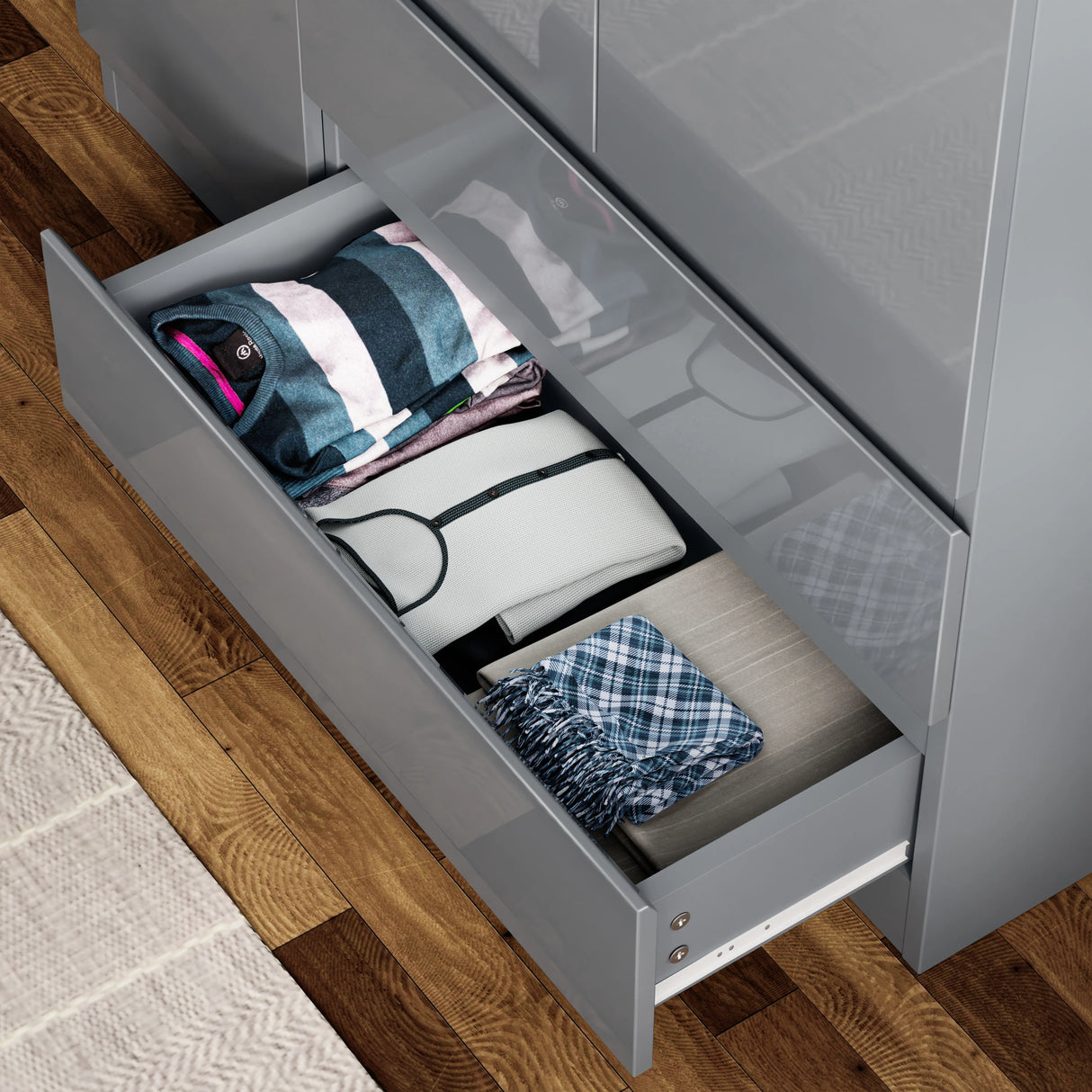 Spacious drawer of grey high gloss wardrobe filled with folded clothes, highlighting its practical storage capacity.