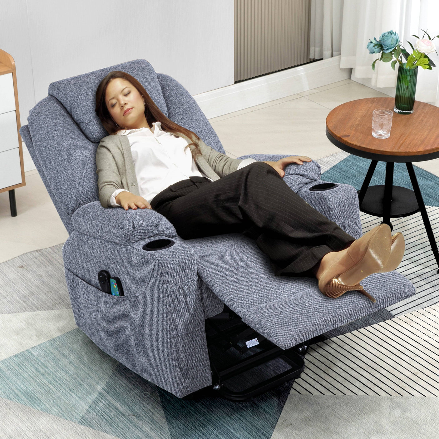 Woman relaxing on grey electric recliner chair with cup holders, extended footrest, and full recline for sleeping comfort.