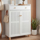 [White] Front view of slatted shoe cabinet with both louvered doors closed and top drawer with wooden knobs
