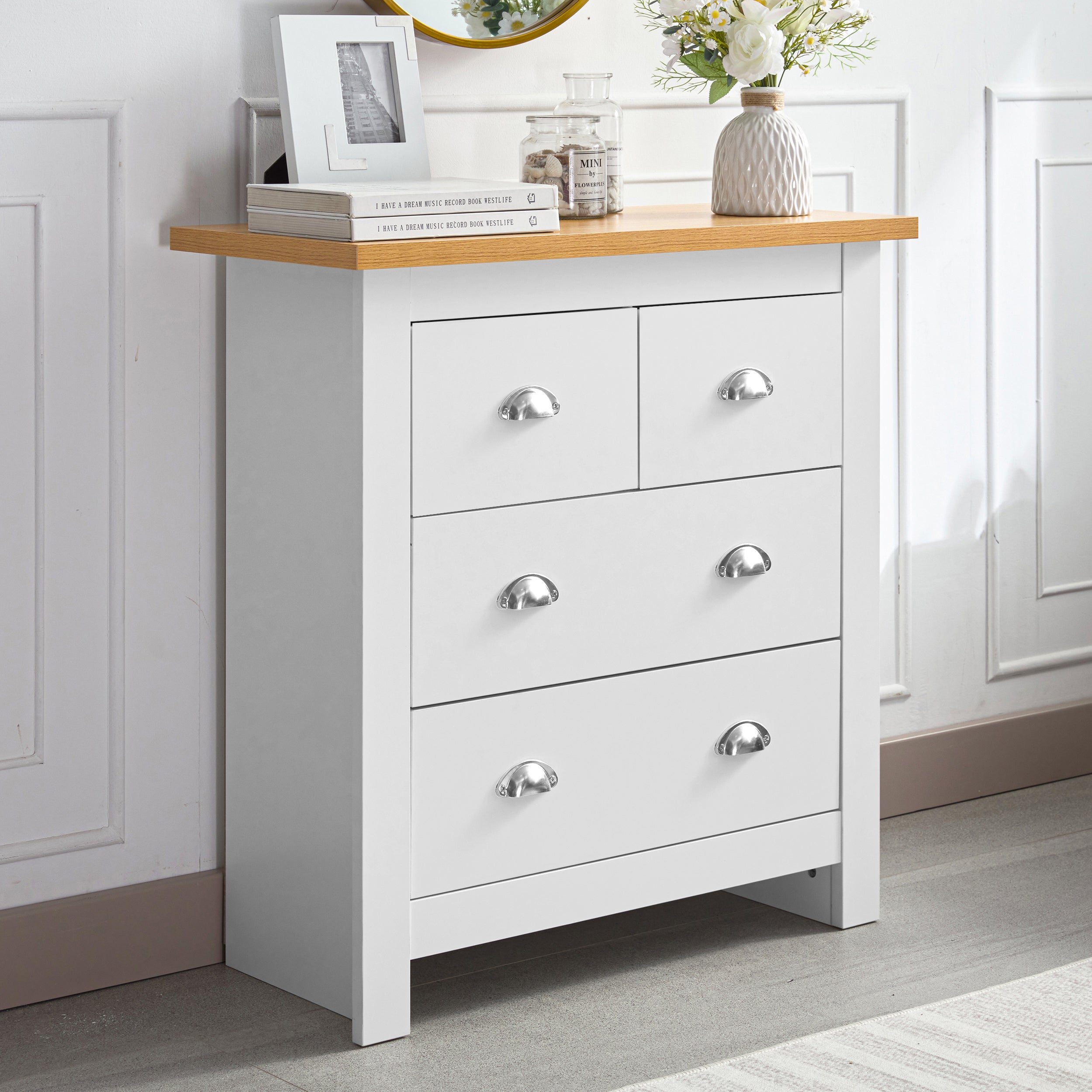 White 6-drawer chest of drawers with a wooden top, decorated with books and a vase with flowers.