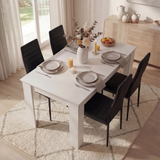 Dining room with a white table set for dinner, black chairs, and decorative elements.
