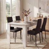 Dining room with a white table and black chairs, featuring a vase of flowers and candles.