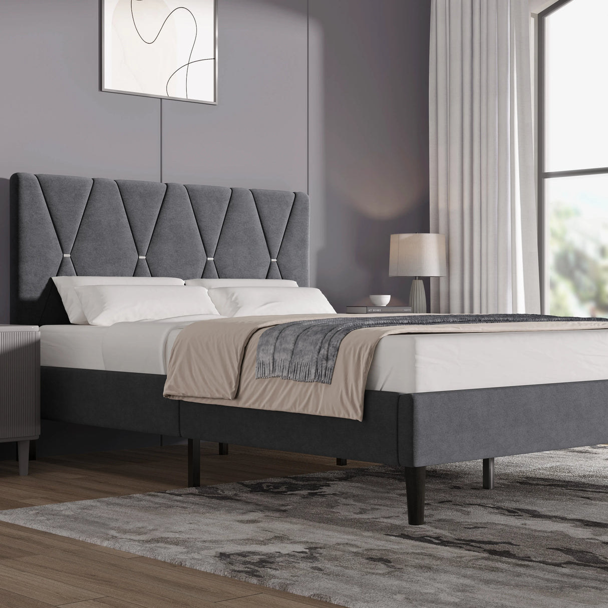 Velvet upholstered bed frame in dark grey with padded adjustable headboard, shown in a modern bedroom with wooden flooring and neutral decor.