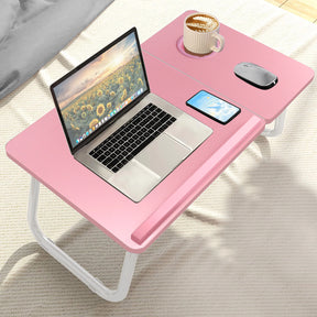 pink small laptop table on a bed featuring phone, tea, and computer gear arranged neatly for relaxation or work
