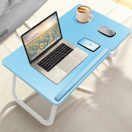 high-angle shot of blue bed laptop table on a bed holding a cup, phone, and a small computer setup