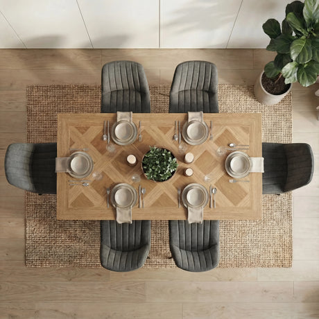 A top-down view of the Aldridge dining table with 6 grey chairs around it. The table is set with plates, cutlery and a plant.
