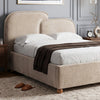 [King | Beige] A beige upholstered bed frame with a tall rounded headboard and matching footboard, shown dressed in white bedding with a dark brown throw blanket