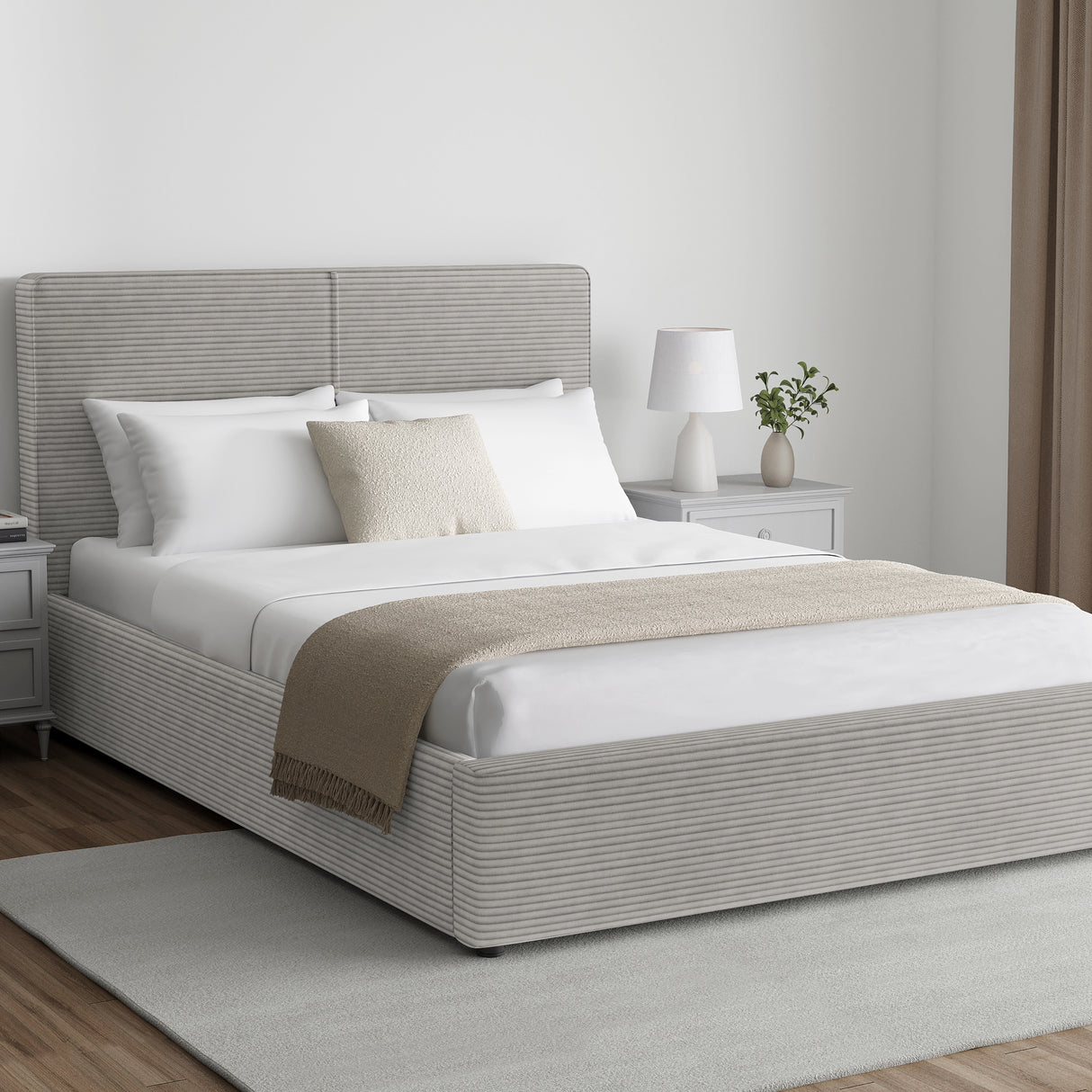 Corduroy ribbed velvet upholstered ottoman bed frame with storage in light grey, shown in a modern bedroom with white bedding and neutral decor.