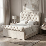 [Beige] Side bedroom view with tall tufted headboard, rolled footboard, layered pillows, lamp, and curtains