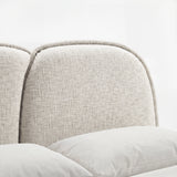 Detail view of a curved padded backrest with soft upholstery fabric texture positioned above neutral bedding