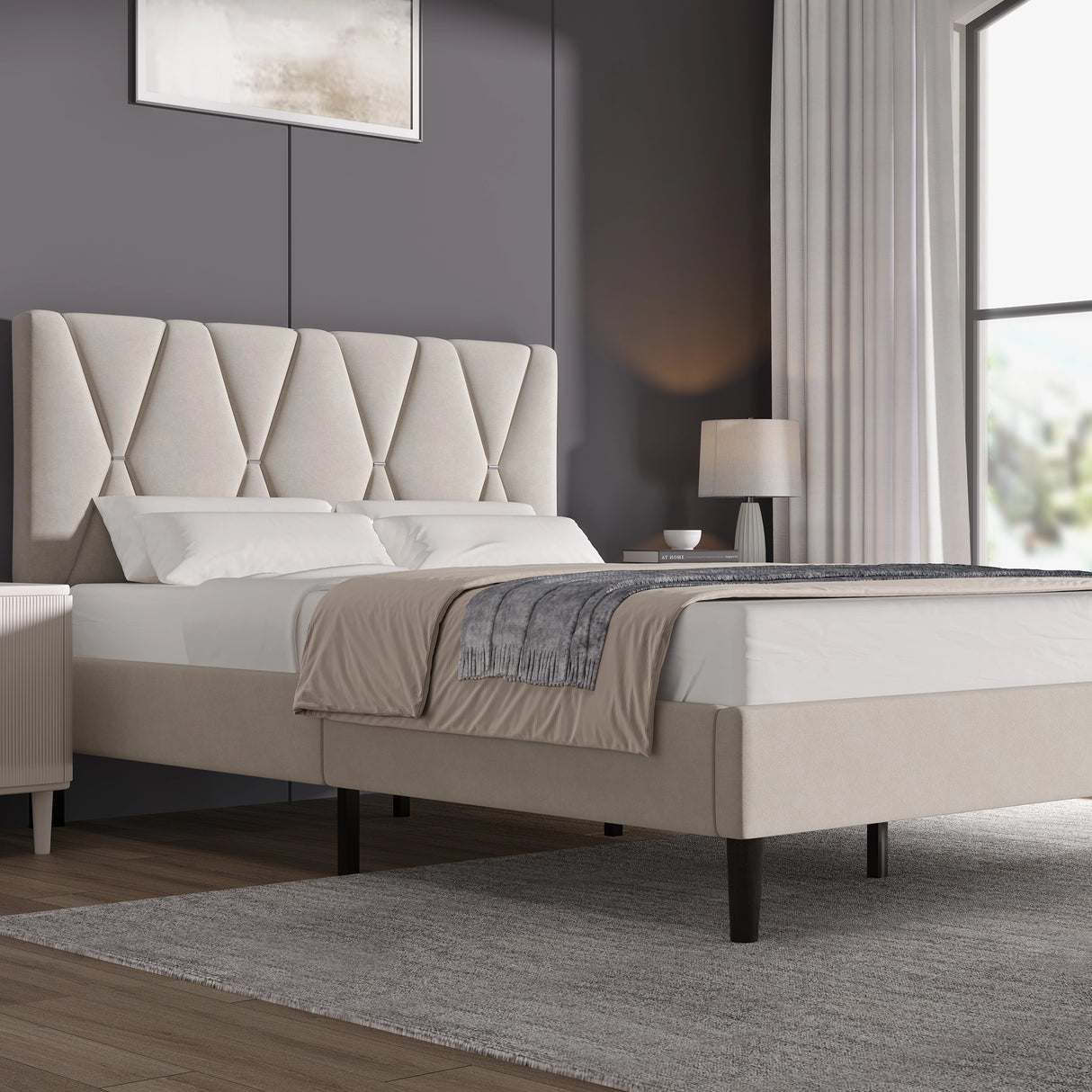 Beige upholstered bed in a modern bedroom setting with a lamp and window.