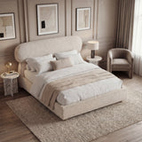 Diagonal view of a beige king bed highlighting the curved headrest profile and low upholstered base