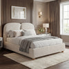 Beige upholstered double bed frame with a soft fabric finish, complemented by simple bedding and a cozy bedroom setting