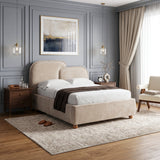 [King | Beige] upholstered bed with a rounded headboard and footboard stands in a styled bedroom with gray paneled walls, white bedding, a dark brown throw blanket, matching nightstands, pendant lights, curtains, and a rug.
