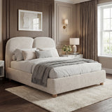 Beige king size bed frame with softly padded base, curved back support, and natural light entering from windows