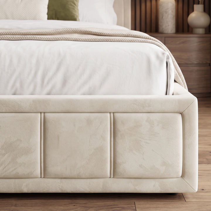 [King | Beige] Front-on view of velvet ottoman storage bed footboard centred between bedside lamps under framed wall art