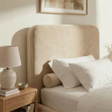 Close view of beige velvet single bed headboard with soft curved shape and padded upholstered finish