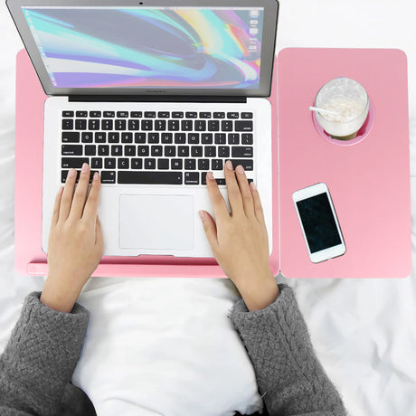 pink laptop table with a pair of hands using the surface while working on a laptop, shown from top view