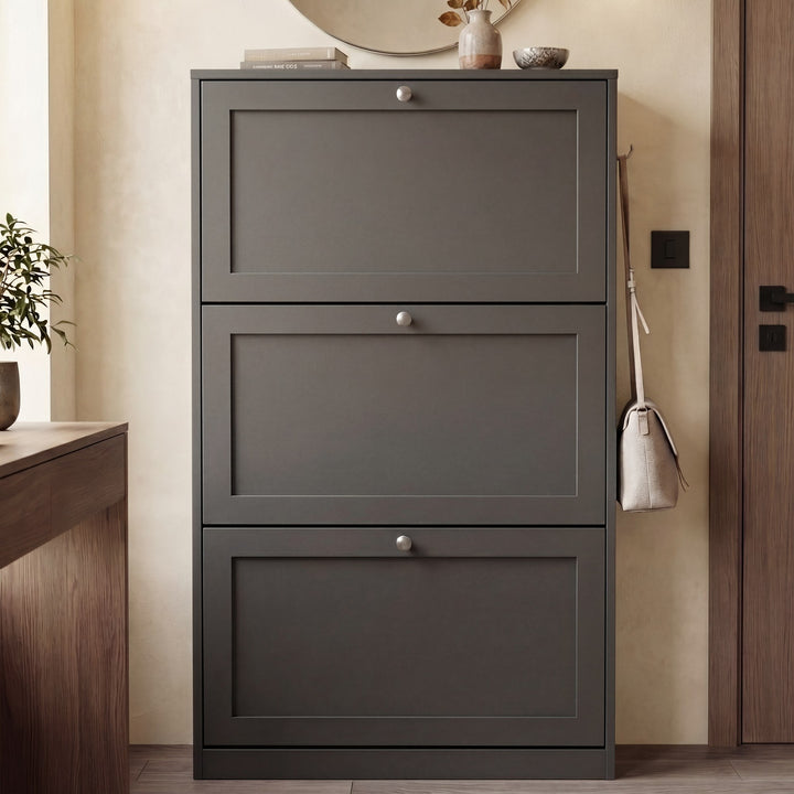 [Grey] Shaker Shoe Cabinet closed three-door flip-front unit in warm neutral hallway with round mirror above and ceramic vase and books on top