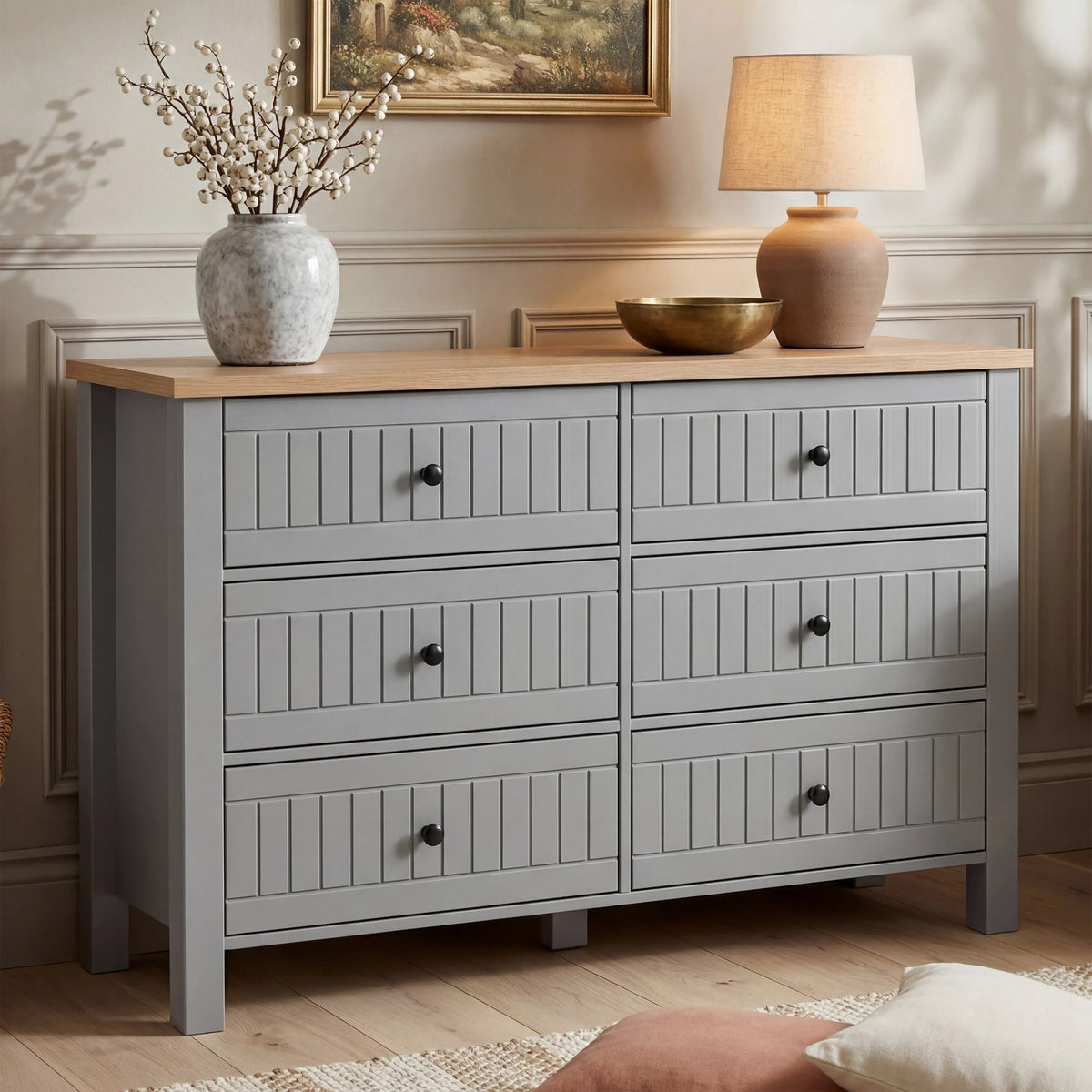 [Grey] Linra large 6 drawer chest front view with vase and table lamp on oak top with framed artwork above