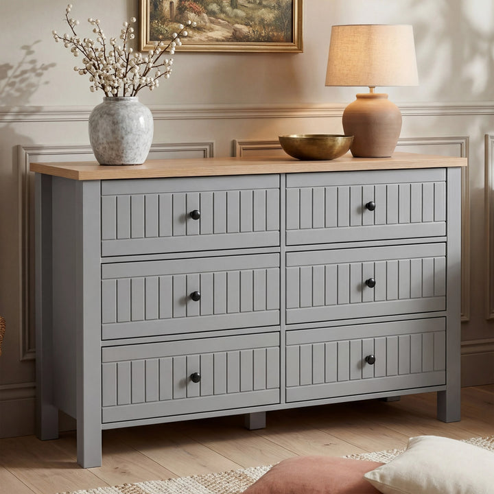 [Grey] Linra large 6 drawer chest front view with vase and table lamp on oak top with framed artwork above